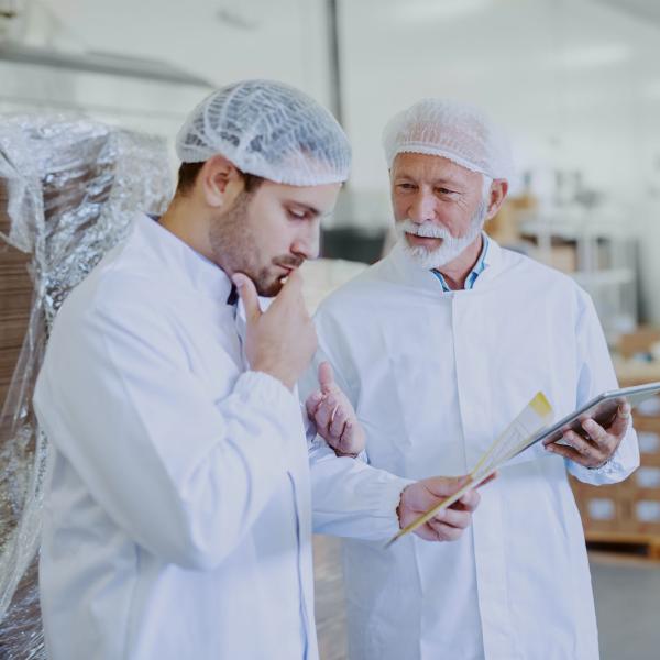 Two men in a factory discussing a food order