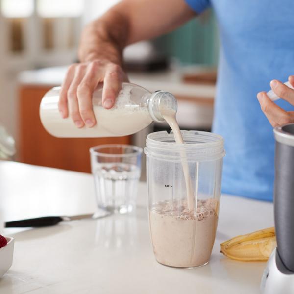 Man pouring protein shake into glass