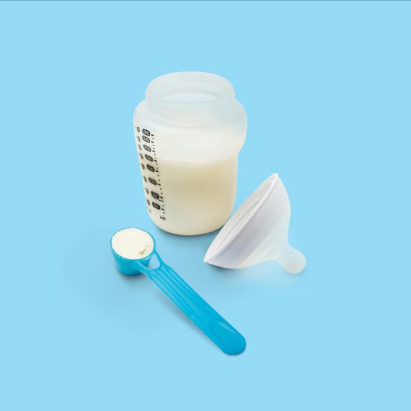 Baby bottle of milk alongside a scoop of infant nutrition formula
