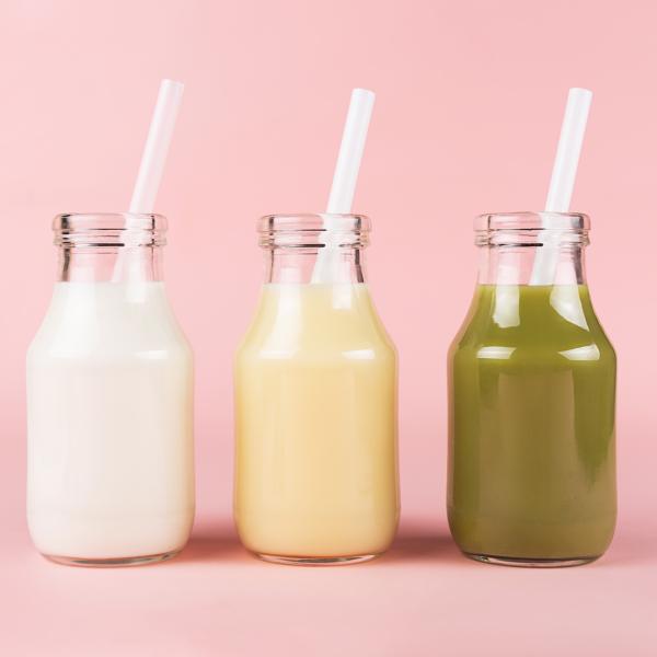Three meal replacement drinks of different colours in small glass bottles