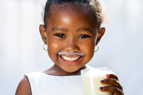 image of smiling child holding a glass of milk