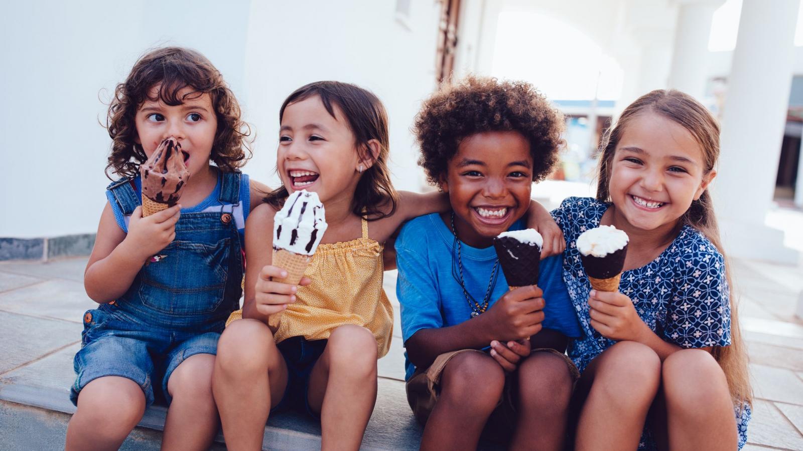 Four children sitting on a step and eating ice cream